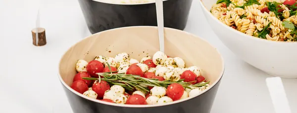 Tomate-Mozzarella-Salat und Nudelsalat in Schalen auf dem Buffet